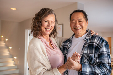 Diverse couple dancing holding hands in modern entryway near floating staircase, framed artwork