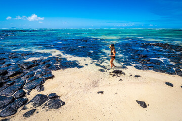 Picturesque view of a little girl playing on the sandy beach of the exotic island of L'îlot...