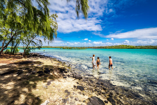 Picturesque view of mother and two children wading through the shallow crystal clear water, exploring the exotic island of L'&icirc;lot Bernache, Mauritius