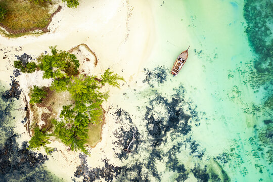 Breathtaking aerial view of a wooden sailboat anchored on the white sand beach of the isolated and paradisiacal island of L'&icirc;lot Bernache, Mauritius
