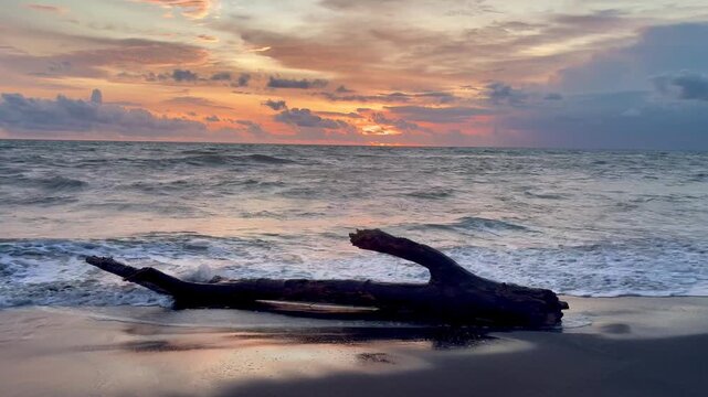 Breathtaking sunset in Bali, Indonesia with big ocean waves and cloudy orange sky