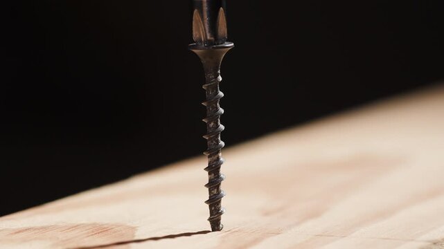 Macro photography of the process: a metal screw being driven into a wooden surface using a screwdriver. Detailed views of the threads, the tool bit, and the wood grain
