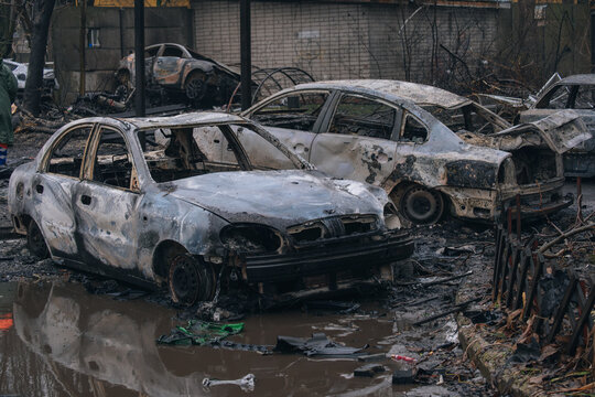 A row of burned-out civilian cars in an area flooded by shelling. Extensive destruction of vehicles and the urban environment in the war zone. A dramatic view of the aftermath of war.