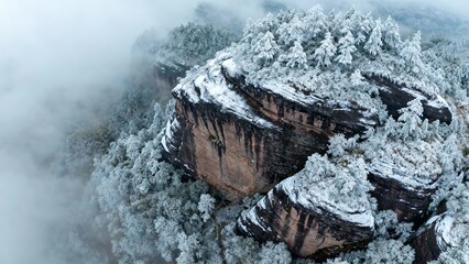 Snow-covered rocky cliffs and frost-laden trees shrouded in mist