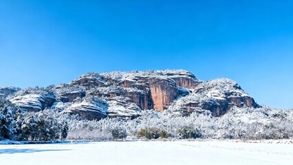 Snow-covered rocky mountain landscape under clear blue sky