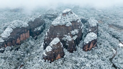 Snow-covered rock formations in a misty forest landscape