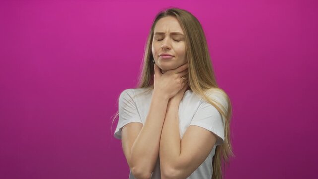 Woman choking holds neck wearing white shirt against pink background expressing discomfort health concept.