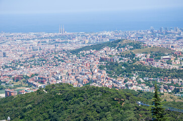 Fototapeta premium Aerial View of Cityscape with Green Hills and Ocean Horizon