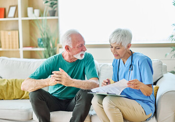 Portrait of a senior doctor or nurse caregiver talking consultation with senior man at home or...