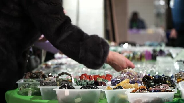 Woman chooses a bracelet made of natural stones. A fair or souvenir shop
