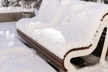 Snow bench winter day A wooden park bench is buried under thick layer of freshly fallen snow