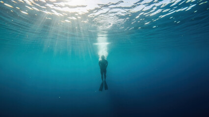 Friends diving off a cliff into clear blue water, sunlight streaming through the surface, capturing a sense of adventure and freedom in the open ocean