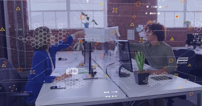 Woman pushing printed chart toward coworker, coworker analyzing business data and typing insights