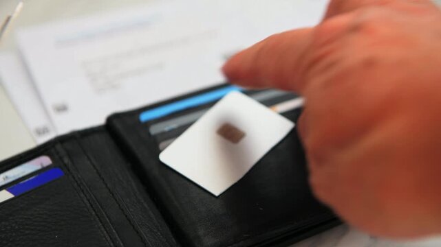 A close up of a person cutting up a bank credit card with an open purse and credit card bills in the background.
