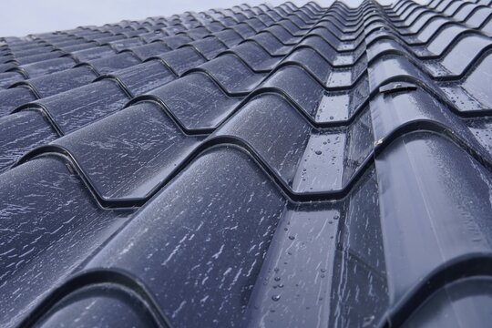 Roofing sandwich panels. Installation of insulated metal sandwich panels. Top view of anthracite-gray metal roofing panels with a tile texture. Bolts with EPDM washers.