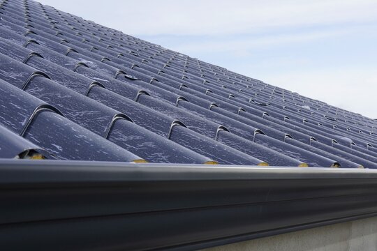 Roofing sandwich panels. Installation of insulated metal sandwich panels. Top view of anthracite-gray metal roofing panels with a tile texture. Bolts with EPDM washers.