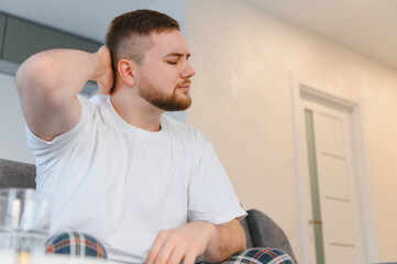 Young man suffering from severe headache and neck pain