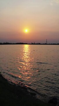 Sunset over calm water with ayam dan anaknya in serene landscape