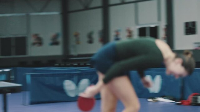 Determined female table tennis player missing a shot