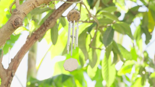 Morocco &ndash; May 8, 2024: Wind chime hanging in a lush riad courtyard surrounded by greenery and traditional architecture.
