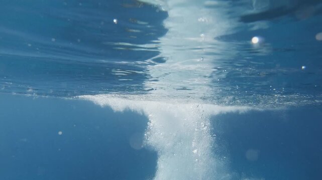 Underwater scene. A young woman dives and swims in the depths of the blue sea