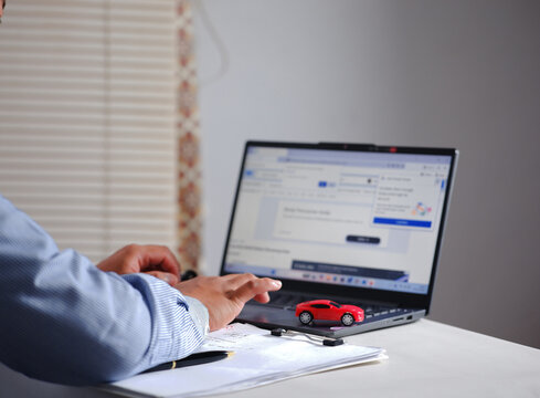 Buying and selling cars online. A man wants to buy a used car. He's browsing through numerous used car listings online on his laptop to compare prices. Many automobiles with picture detail.
