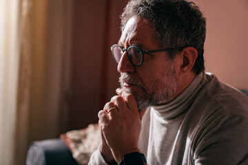 Middle aged man in quiet contemplation at home, reflective moment on sofa