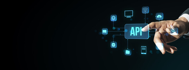 Businessman's hand interacting with digital API interface icons representing software integration and cloud computing on dark background.