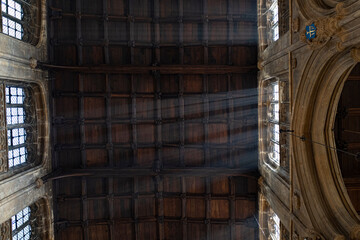 Rays of light entering through a window in a gothic Church with a wooden ceiling in the Cotswolds, England