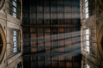 Rays of light entering through a window in a gothic Church with a wooden ceiling in the Cotswolds, England