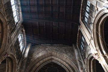 Rays of light entering through a window in a gothic Church with a wooden ceiling in the Cotswolds, England