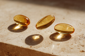 Healthy golden vitamin omega 3 oil capsules on beige stone background. Dietary supplements and health benefits.