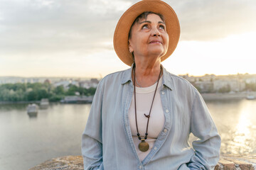 Elegant Senior Woman in Hat Enjoying Summer Sunset in the City