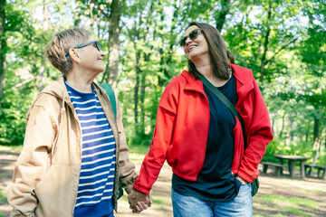 Fototapeta premium Mother and Daughter Walking Hand in Hand in Summer Park Celebrating Mother’s Day