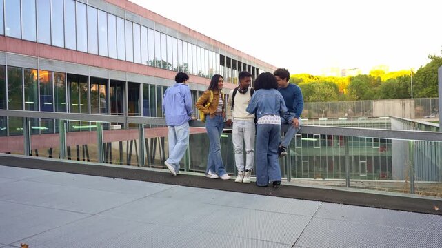 Group of diverse college students socializing and talking together on a campus walkway. Young people enjoying a break from class outdoors