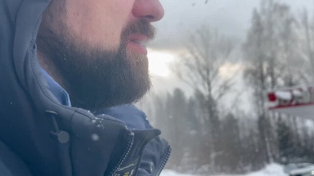 Close-up of a man smoking, video. A man with a beard in a winter jacket.