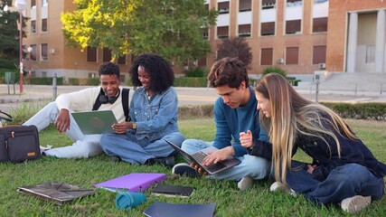 Young diverse students collaborating on a project with laptops. Happy friends sitting on the green grass of the university campus studying - Powered by Adobe