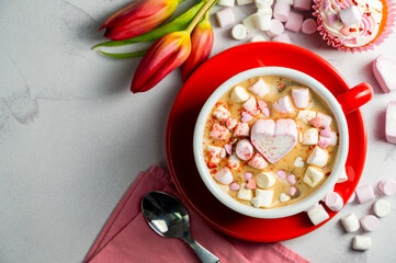Valentine's Day background. Red cup of coffee with heart shaped marshmallows and ret tulips