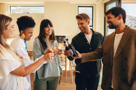 Friends celebrating with cheers and drinks in a stylish home setting