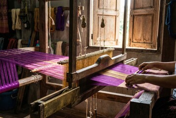 Artisan hands weaving traditional purple silk fabric on loom