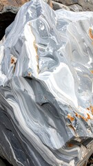 Marble rock A light grey rock with swirling white and gold streaks and natural ridges on a sunny day