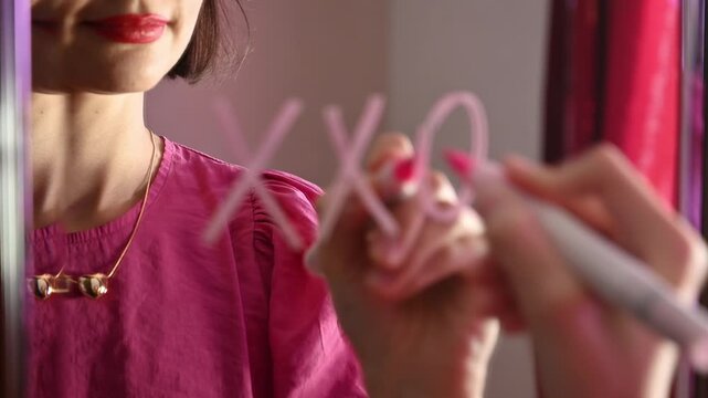Love note. A girl draws the message XXOO on her mirror, a symbol of hugs and kisses with a hidden love meaning for Valentines Day