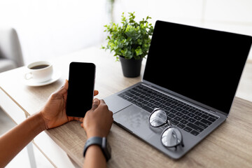 Cropped view of young black lady with smartphone and laptop shopping online, using new mobile app...
