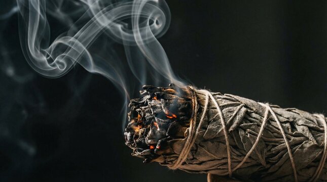 Swirling smoke from burning white sage smudge stick