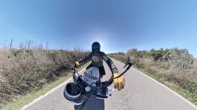 Chico con casco oscuro en motocicleta cl&aacute;sica rodando por carretera y bosque en d&iacute;a soleado ,toma grabada en 4k