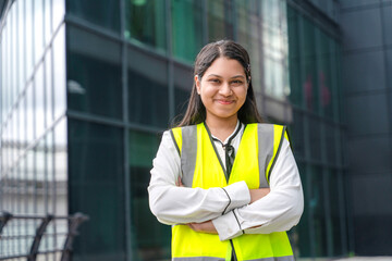 Young woman in safety vest stands confidently outside a modern building © Iryna