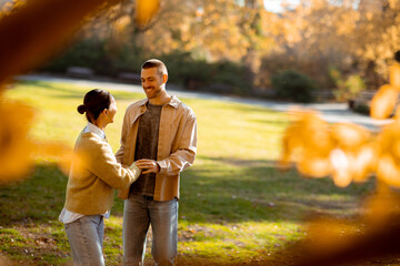 Couple enjoying a sunny autumn day, dancing joyfully in a vibrant park setting