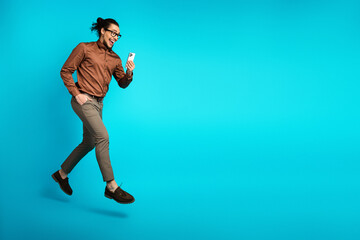 Young professional man using smartphone against turquoise background demonstrating style and...