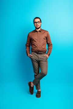 Trendy young male in formalwear posing confidently against turquoise vertical background