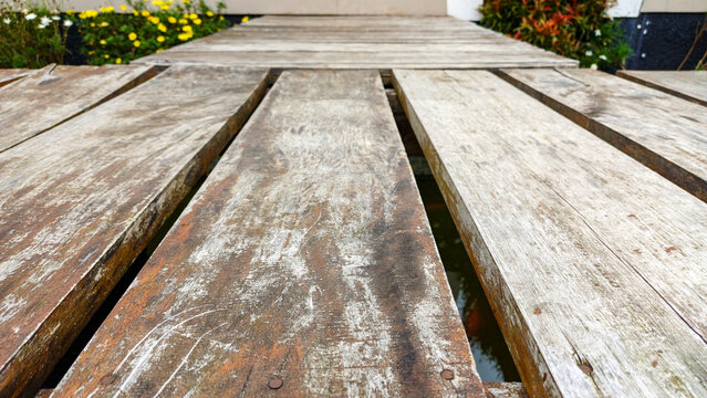 Close-up texture of weathered wooden boardwalk planks. Rustic timber surface with aged grain, peeling paint, and perspective lines. Natural outdoor background for design.